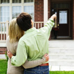 couple pointing at house image